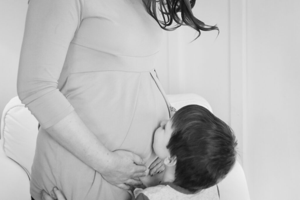 Un enfant d'âge préscolaire embrasse le ventre de sa mère enceinte's Pregnant Belly